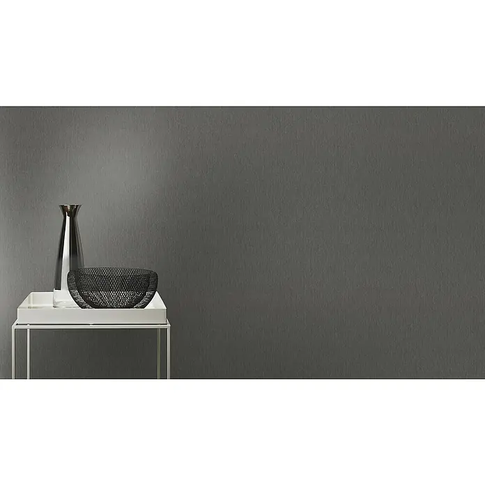 Rasch Sky Lounge Vliestapete Metallic-Uni - Graphit, Uni, 10,05 x 0,53 m - Ein elegantes Stillleben mit einer schlanken Glasvase und einer dekorativen Metallschale auf einem modernen weißen Tisch.