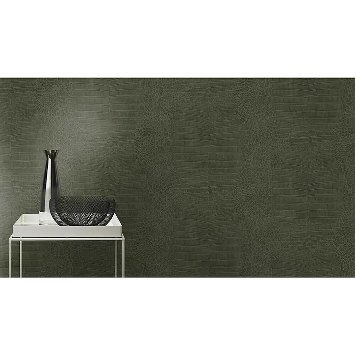 Rasch African Queen III Vliestapete Krokodilleder - Dunkelgrün, Lederoptik, 10,05 x 0,53 m - Elegantes Stillleben mit einer schlanken Vase und einer dekorativen Schale auf einem stilvollen Beistelltisch vor einem luxuriösen Krokodilleder-Hintergrund.