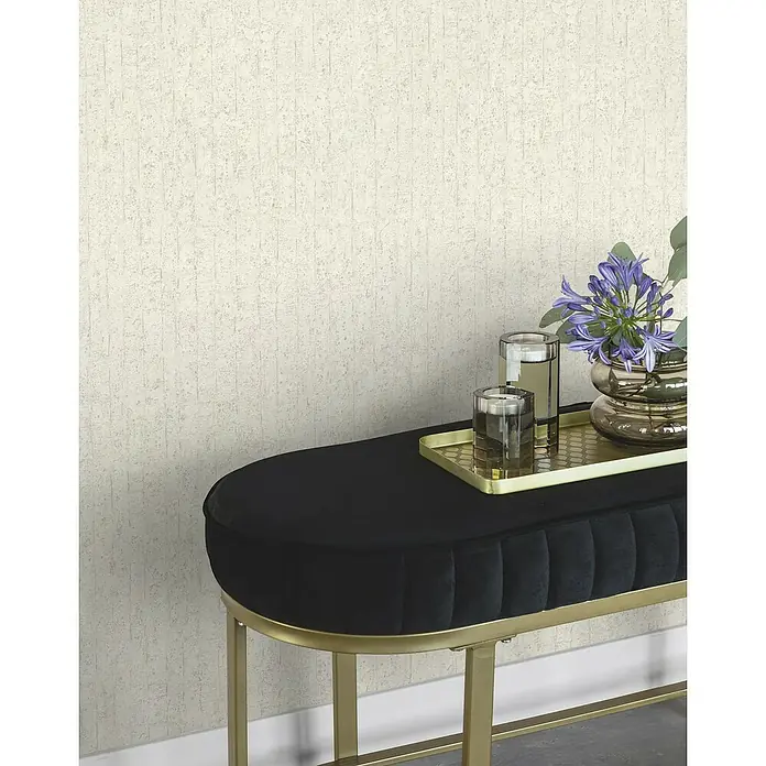 Rasch Factory V Vliestapete Betonoptik-Uni - Kalkstein, Steinoptik, 10,05 x 0,53 m - Nahaufnahme einer eleganten, schwarzen Samtbank mit goldenen Beinen, die eine stilvolle Dekoration mit Blumen und Gläsern trägt.
