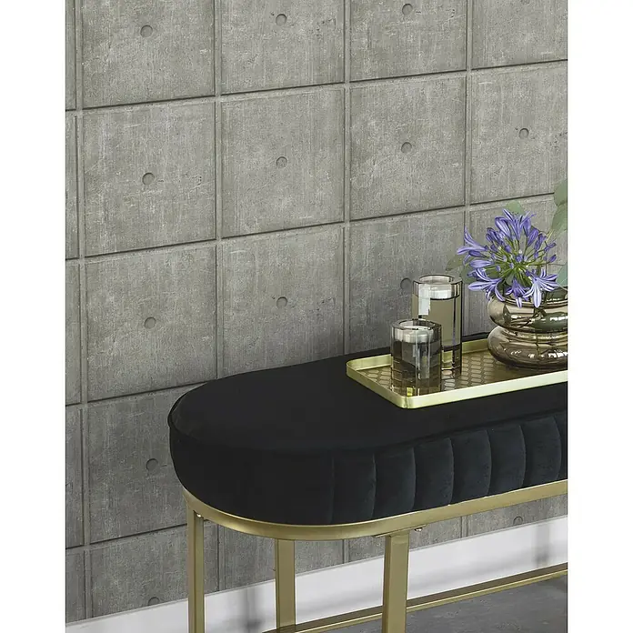 Rasch Factory V Vliestapete Zementfliese - Concrete, Steinoptik, 10,05 x 0,53 m - Nahaufnahme einer stilvollen schwarzen Sitzbank mit goldenen Beinen, auf der sich Gläser und eine Vase mit Blumen befinden. Perfekt für jedes moderne Zuhause.