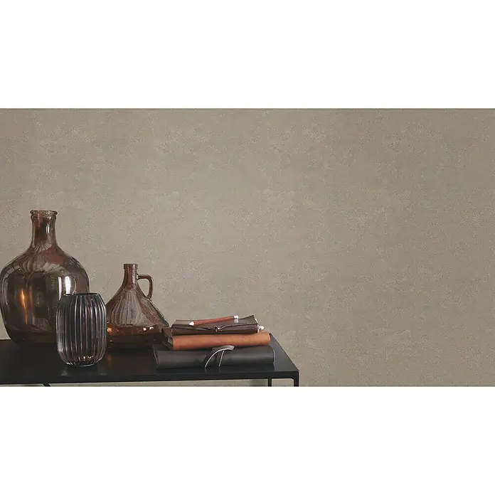 Rasch Factory V Vliestapete Metalloptik - Hellbraun, Uni, 10,05 x 0,53 m - Stilleben mit verschiedenen Glasgefäßen und gestapelten Notizbüchern auf einem kleinen Tisch. Dekorative Wohnaccessoires im Fokus.