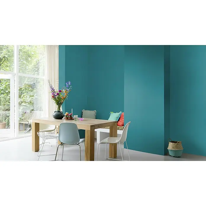 Rasch Symphony Vliestapete Leinen-Uni - Türkisblau, Uni, 10,05 x 0,53 m - Eine stilvolle Esszene mit einem Holztisch und modernen Stühlen vor einer azurblauen Wand. Frische Blumen und dezente Dekorationen ergänzen den Raum.
