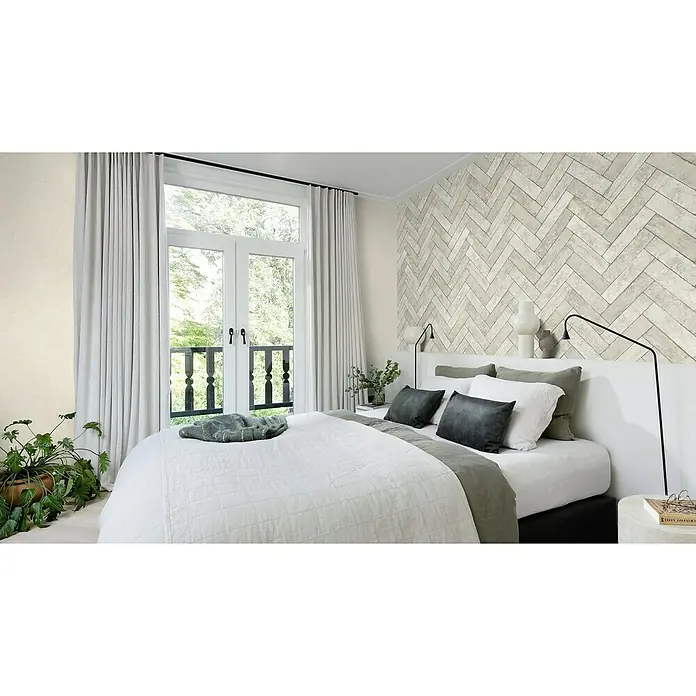 Rasch Factory V Vliestapete Bricks - Schiefergrau, Steinoptik, 10,05 x 0,53 m - Schlafzimmer mit einem großen Bett mit weißer Bettwäsche und grauen Kissen vor einer Akzentwand mit Fischgrätenmuster.