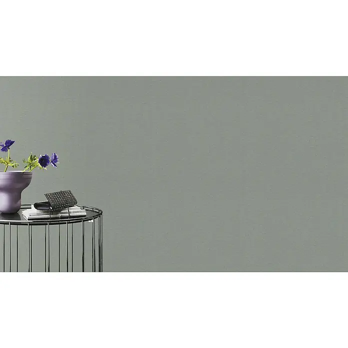 Rasch Country Charme Vliestapete Textil-Uni - Grau, Uni, 10,05 x 0,53 m - Nahaufnahme eines Beistelltisches mit einer Vase mit Blumen, Büchern und einer modischen Handtasche auf einer eleganten grauen Leinwand.