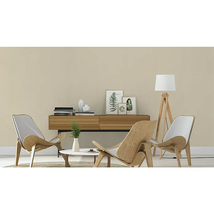 Rasch Wall Textures VI Vliestapete Uni - Taupe, Uni, 10,05 x 0,53 m - Ein Wohnzimmer mit zwei modernen Holzstühlen, einem Beistelltisch mit Deko und einer Kommode mit Pflanzen und Bildern. Die Lampe rundet das Ambiente ab.