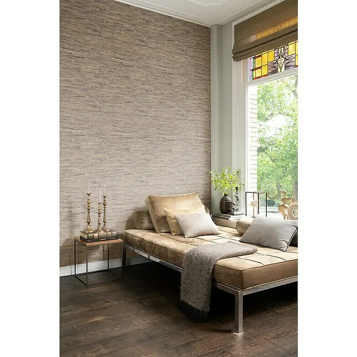 Rasch Curiosity Vliestapete Holzoptik - Hellbraun, Holzoptik, 10,05 x 0,53 m - Gemütliches Interieur mit einem eleganten Tagesbett mit beigen Kissen und einer dekorativen Wand, das eine einladende Atmosphäre schafft.
