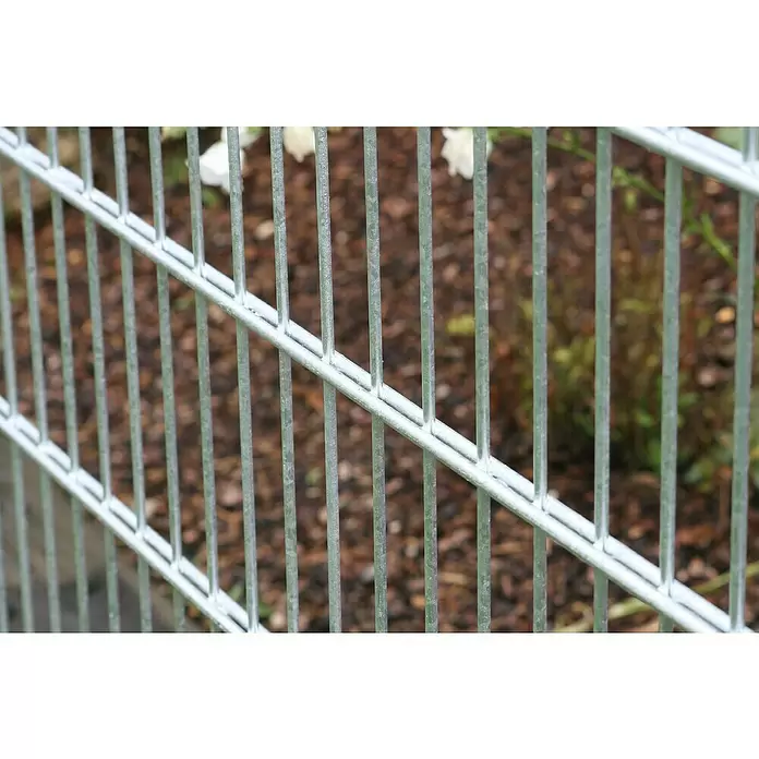 Kraus Mattenzaun - 201 x 123 cm, Feuerverzinkt - Nahaufnahme eines verzinkten Metallgitterzauns mit vertikalen und horizontalen Stäben vor unscharfem Gartenhintergrund.