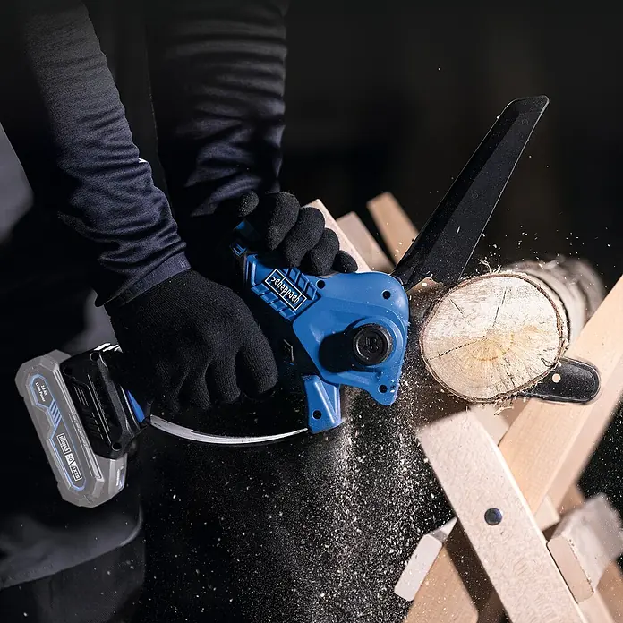 Scheppach IXES 20V Einhand-Akku-Kettensäge BC-PS150-X - 20 V, Li-Ionen, Ohne Akku - Nahaufnahme einer Scheppach Akku-Kettensäge im Einsatz, die ein Holzstück durchtrennt. Sichtbar sind die Sägespäne.