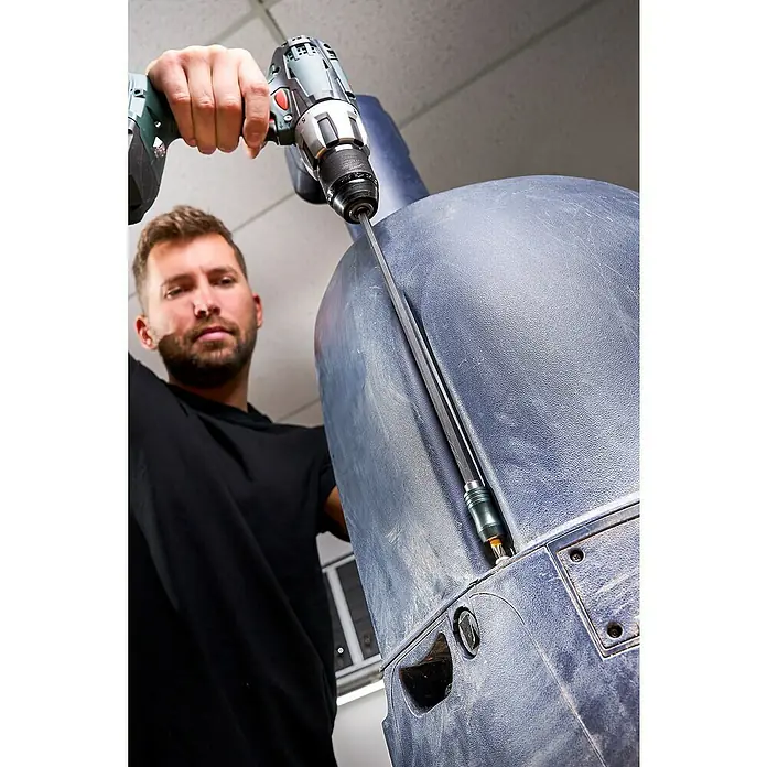 Wolfcraft Bithalter - Länge: 300 mm - Ein Mann benutzt einen Akku-Bohrschrauber mit Verlängerung, um an einem großen blauen Objekt zu arbeiten. Das Werkzeug steht im Fokus.
