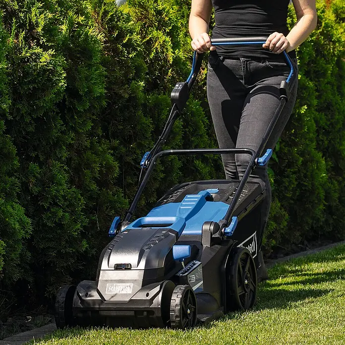 Scheppach IXES 20V Akku-Rasenmäher BC-MP430-X - 20 V, Ohne Akku, Schnittbreite: 43 cm - Eine Frau benutzt einen Scheppach Akku-Rasenmäher im Garten, um den Rasen zu mähen. Der Rasenmäher ist schwarz und blau.