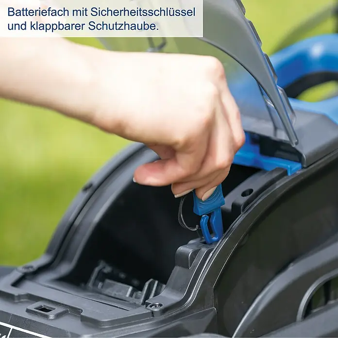 Scheppach IXES 20V Akku-Rasenmäher BC-MP320-X - 20 V, 1 Akku, 4 Ah, Schnittbreite: 32 cm - Detailansicht des Batteriefachs mit Sicherheitsschlüssel und klappbarer Schutzhaube eines Gartengeräts.