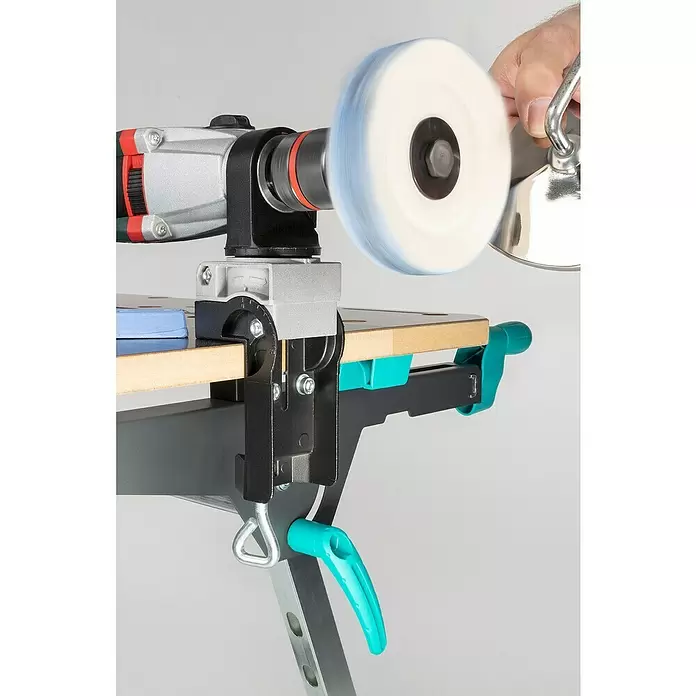 Wolfcraft Soporte de taladro - Apertura máxima: 60 mm - Un taladro plateado con rueda de pulido giratoria, montado en una abrazadera negra y turquesa en un banco, puliendo un objeto a mano.