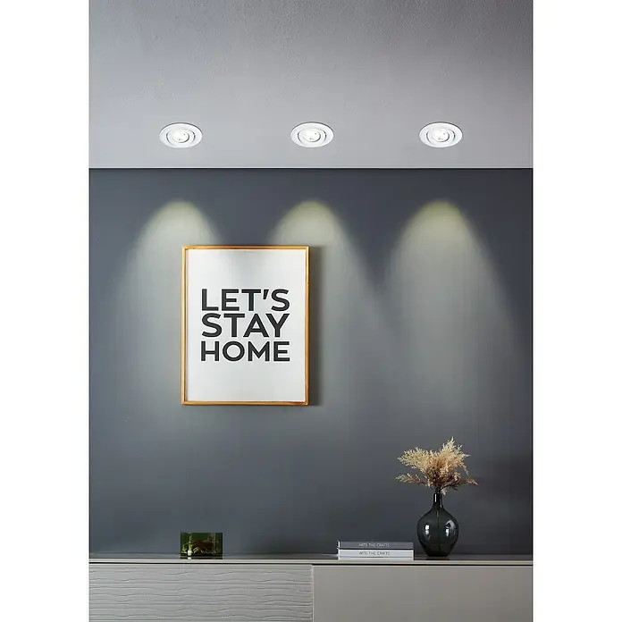 Eglo LED-Einbauleuchten-Set rund SALICETO MINI-PUCK 2 - 4,2 W, Ø x H: 7,7 x 2,3 cm, Weiß, Warmweiß - Drei LED-Deckenspots beleuchten ein gerahmtes "Let's Stay Home"-Poster über einer Kommode mit Vasen- und Buchdekoration.