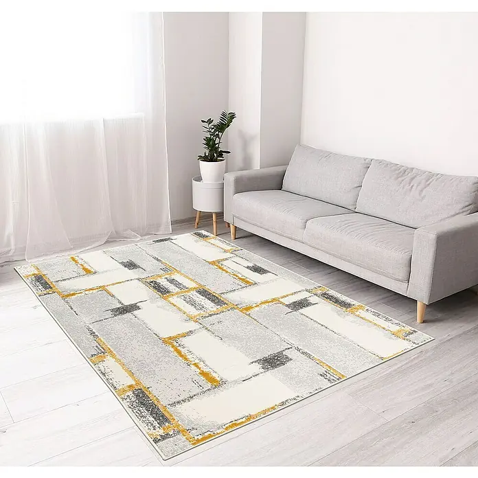 Alfombra de pelo corto Difuminado - Mostaza, 170 x 120 cm, Polipropileno - Una alfombra gris con un patrón abstracto en amarillo y negro se encuentra en una habitación luminosa debajo de un sofá gris.
