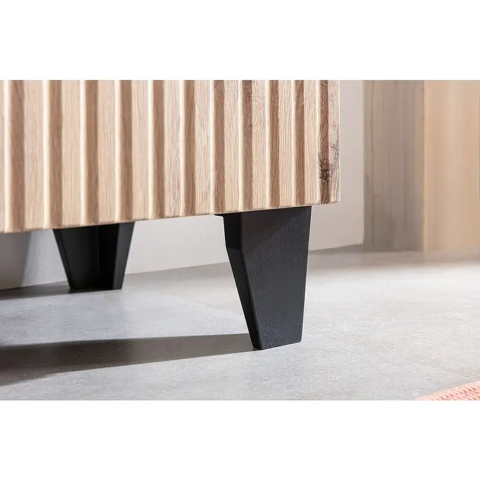 Riva Badmöbel-Set Rigato - 58,5 cm, Eiche/Schwarz, Strukturiert - Nahaufnahme eines hellen Holzschranks mit schwarzen, konisch zulaufenden Metallbeinen auf einem grauen Boden.