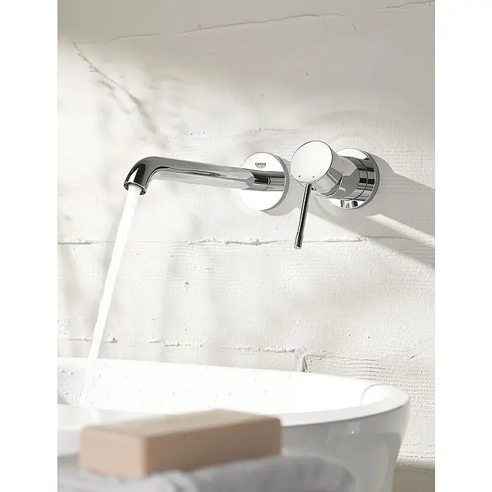 Grohe Essence Waschtischarmatur M - Wandmontage, Chrom, Glänzend - Einhand-Wandbatterie von Grohe mit einem Auslauf aus dem Wasser fließt in ein Waschbecken, daneben eine Seife.