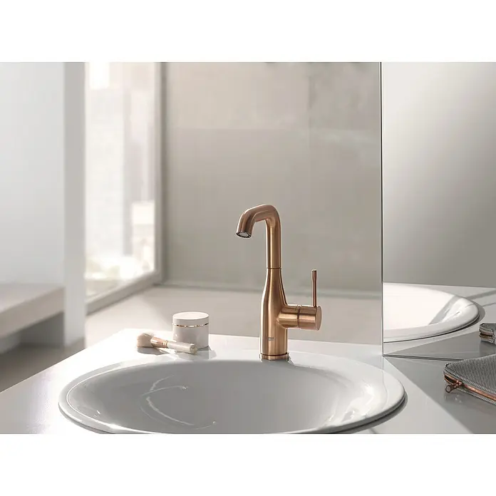 Grohe Essence New Waschtischarmatur L-Size - Mit Zugstange, Warm Sunset, Matt - Nahaufnahme eines eleganten, goldenen Wasserhahns in einem modernen Badezimmer, der Stil und Funktionalität vereint.