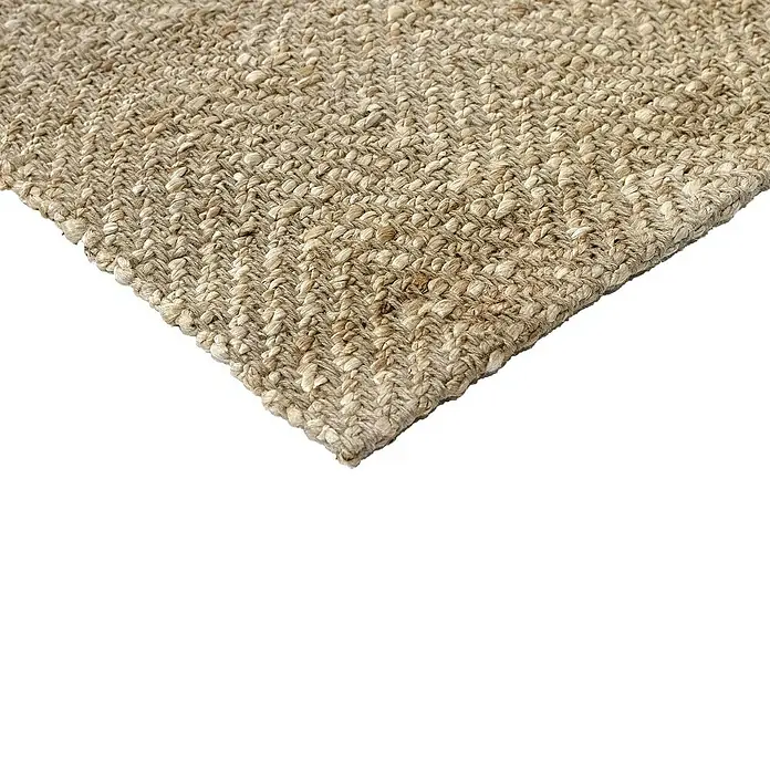 Alfombra de yute Alcázar - Natural, 290 x 200 cm, 100% yute - Primer plano de una alfombra de fibra natural tejida, mostrando una esquina con una textura visible, dando una sensación rústica y acogedora.