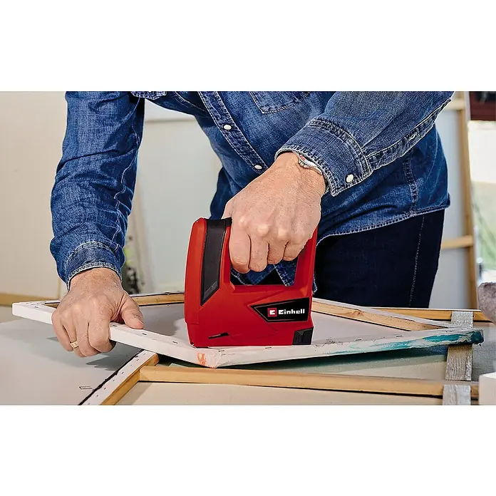 Einhell Classic Akku-Tacker TC-CT 3,6 Li - 3,6 V, 1 Akku, 1.300 mAh, Klammertiefe: 6 mm - 14 mm - Eine Person benutzt einen roten Einhell Tacker, um eine Leinwand auf einen Rahmen zu spannen, was die Funktionalität des Geräts hervorhebt.