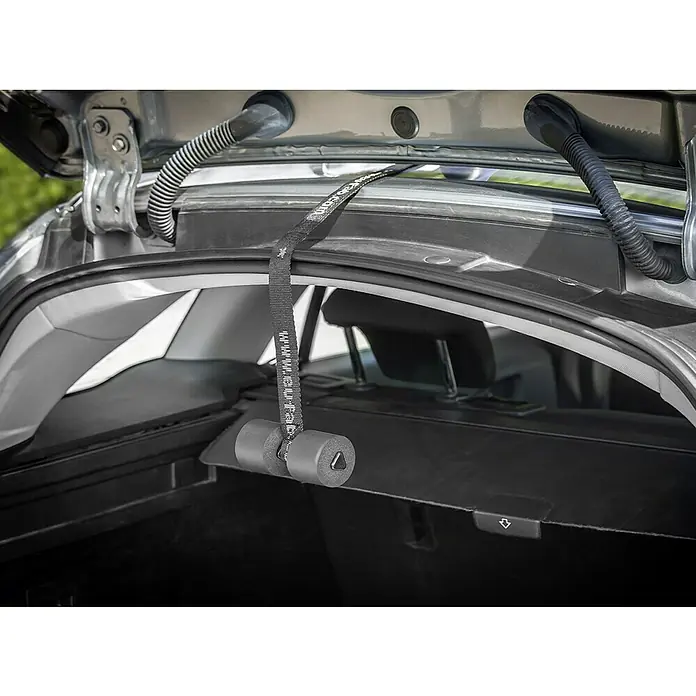Eufab Fahrradträger Amber IV - Geeignet für: 4 Fahrräder, Passend für: Fahrzeuge mit Anhängerkupplung - Detailansicht eines schwarzen Kofferraumrollo-Haltegurts mit Schaumstoffgriffen in einem Auto. Der Gurt sichert die Laderaumabdeckung.