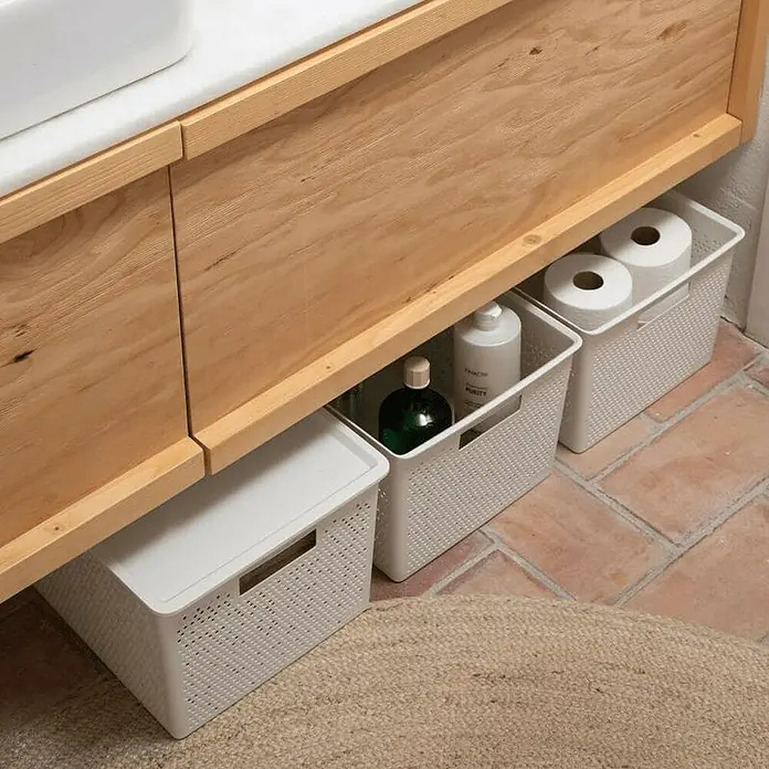Tatay Bohol Cesta para baño - L x An x Al: 39 x 39 x 21,5 cm, Blanco sky - Un primer plano de tres cestas de almacenamiento blancas debajo de un gabinete de madera clara que contiene productos de limpieza y papel higiénico.