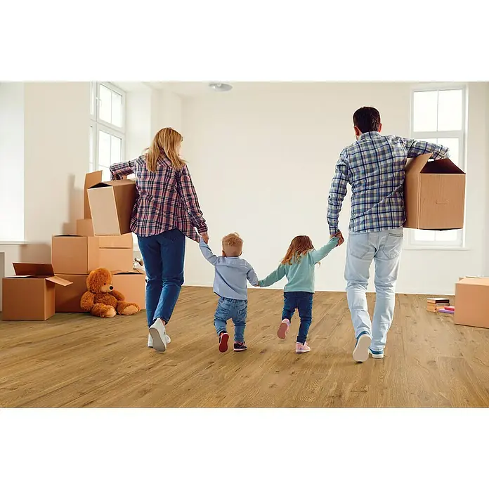 Decolife Designbodenmuster Naturestyle Pure Oak Terra - 28 x 16 x 9 mm, Landhausdiele, Oak Terra - Familie zieht in ein neues Zuhause mit hellen Holzböden, Umzugskartons und einem Teddybär, was eine warme, einladende Atmosphäre schafft.