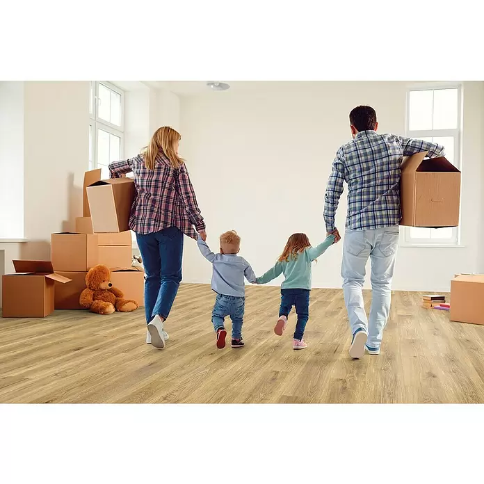 Decolife Designbodenmuster Naturestyle Pure Oak Nature - 28 x 16 x 9 mm, Landhausdiele, Oak Nature - Familie geht auf hellem Laminatboden in einem neuen Zuhause mit Umzugskartons.