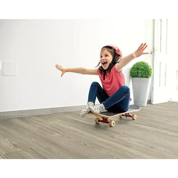 Decolife Designboden Naturestyle Pure - Oak Rock, Landhausdiele, 1.220 x 185 x 9 mm - Kind auf einem Skateboard im Innenbereich. Der Fokus liegt auf dem modernen Bodenbelag, der den Raum aufwertet.\n