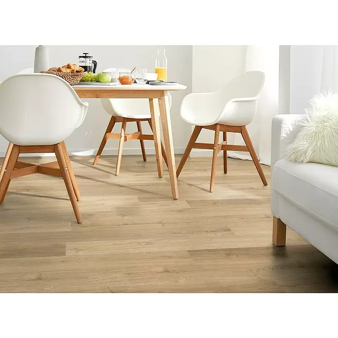 Decolife Designbodenmuster Freestyle Access Hazel Oak - 280 x 160 x 9 mm, Landhausdiele, Hazel Oak - Helle Holzoptik-Bodenplanken in einem hellen Ess- und Wohnbereich mit weißen Möbeln.