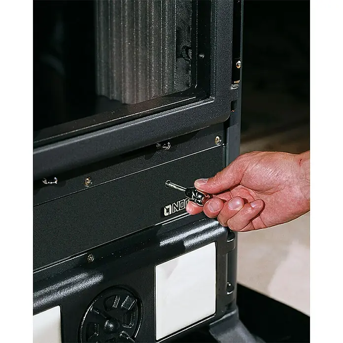 La Nordica Kaminofen Rosella R1 - 11 W, Raumheizvermögen: 252 m³, Material Verkleidung: Keramik, Schwarz/Weiß - Ein Mann bedient einen Nordan Stove Holzofen. Die Tür und der Griff des Ofens sind im Fokus, was die Qualität und Funktionalität betont.