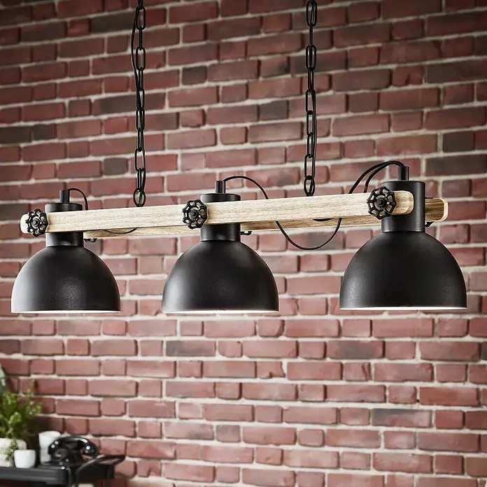 Eglo Lubenham Pendelleuchte - 84 W, L x B x H: 90 x 20 x 110 cm, Schwarz/Braun, E27, 3 Stk. - Eine rustikale Hängelampe mit drei schwarzen Lampenschirmen und einem Holzbalken vor einer Backsteinwand.
