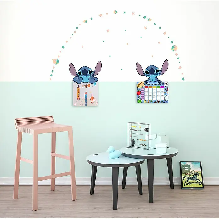 Komar Wandtattoo Stitch Dream - Bunt, 49 -tlg. - Ein Kinderzimmer mit einem pinkfarbenen Hocker, runden Tischen und farbenfrohen Wanddekorationen, die eine verspielte Atmosphäre schaffen.