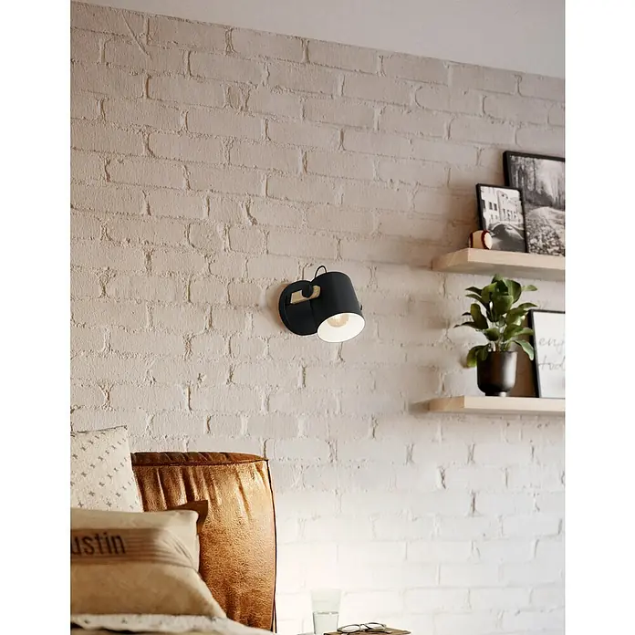 Eglo Hornwood Wandleuchte rund - 28 W, Schwarz, E27 - Wandleuchte mit schwarzem Schirm beleuchtet eine gemütliche Ecke mit Ziegelwand und Holzregalen.