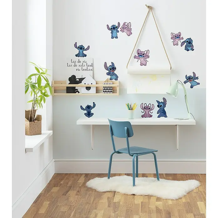 Komar Wandtattoo Stitch & Angel Happy - Bunt, 12 -tlg. - Ein Kinderzimmer mit Stitch Wandaufklebern, die eine verspielte und farbenfrohe Atmosphäre schaffen. Der Teppich und der Stuhl runden das Gesamtbild ab.