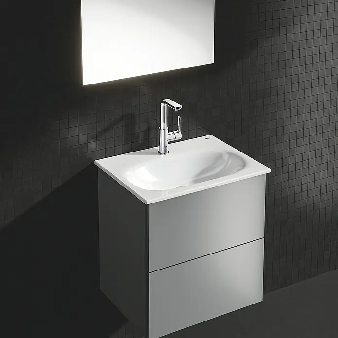 Grohe Lineare Waschtischarmatur L-Size - Chrom, Glänzend - Ein moderner grauer Waschtisch mit einem weißen Waschbecken und einem beleuchteten Spiegel, der eine elegante Badezimmerlösung bietet.