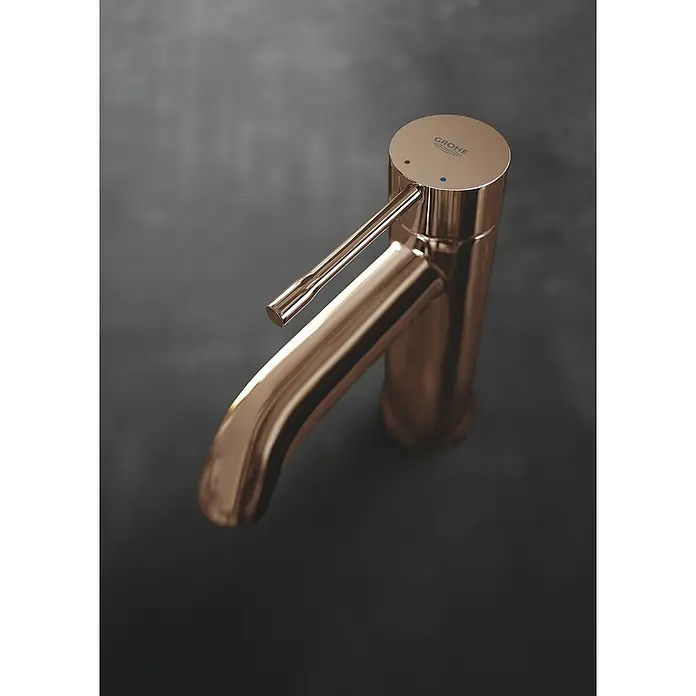 Grohe Essence New Waschtischarmatur S-Size - Mit Zugstange, Warm Sunset, Glänzend - Nahaufnahme einer eleganten Grohe-Armatur in Roségold vor einem dunklen Hintergrund, die hochwertige Verarbeitung und modernes Design hervorhebt.