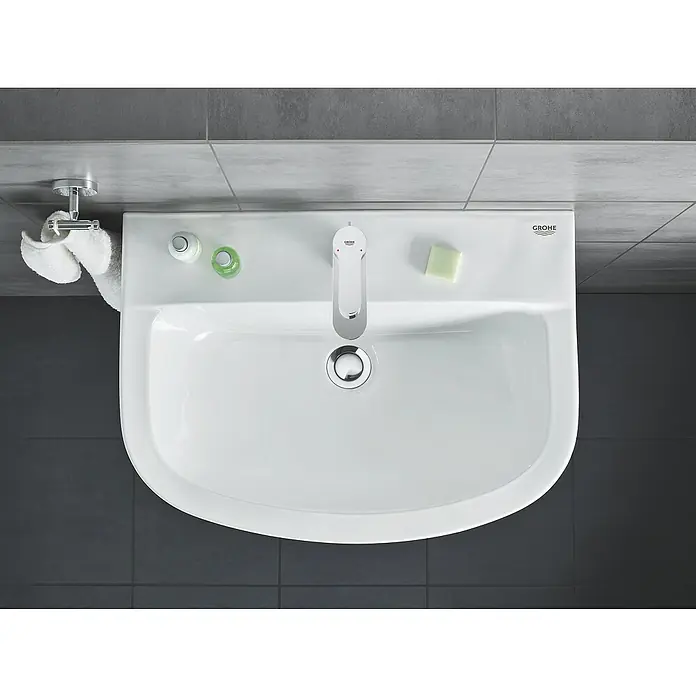 Grohe Waschtischarmatur Bauedge S-Size - Chrom, Glänzend - Draufsicht auf ein weißes Grohe Waschbecken mit Armatur, Seife und Handtuchhalter. Das Waschbecken ist sauber und modern.
