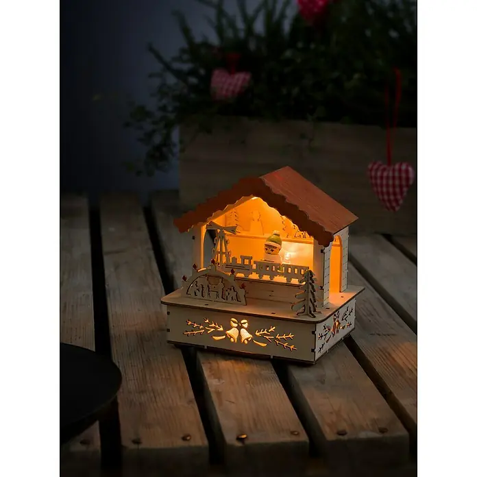 Konstsmide LED-Holzsilhouette - Braun/Bunt, Batteriebetrieben, Warmweiß - Weihnachtliche Holzdekoration: Ein beleuchtetes, detailreiches Holzhaus mit filigranen Ausschnitten und warmem Lichtschein für festliche Stimmung.