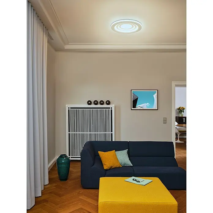 Ledvance LED-Deckenleuchte rund - 42 W, Ø x H: 50,5 x 6 cm, Weiß, Warmweiß - Ein modernes Wohnzimmer mit einer stilvollen Deckenleuchte, einem blauen Sofa und einem gelben Hocker. Elegantes Design für gemütliches Wohnen.