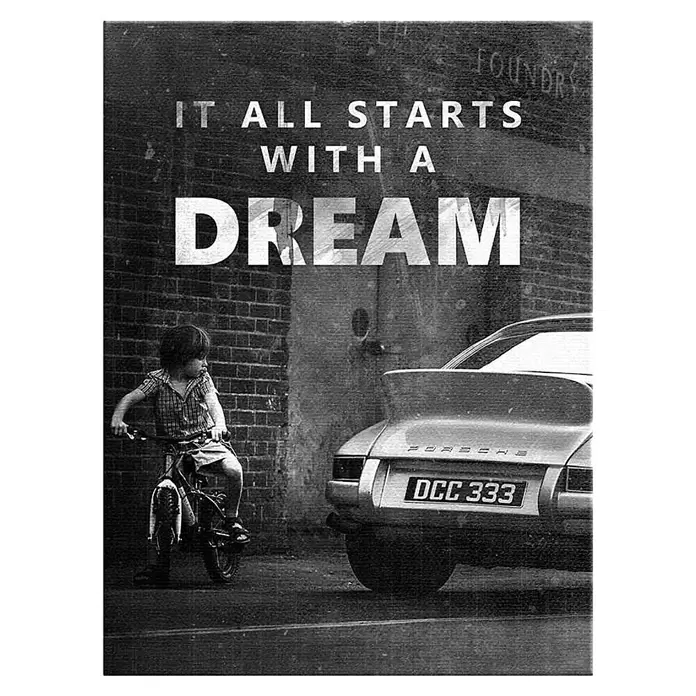 Dotcomcanvas Leinwandbild - It All Starts With A Dream, B x H: 75 x 100 cm - Schwarz-weiß-Poster: Kind auf Fahrrad blickt auf Porsche, Wandtext: "IT ALL STARTS WITH A DREAM".
