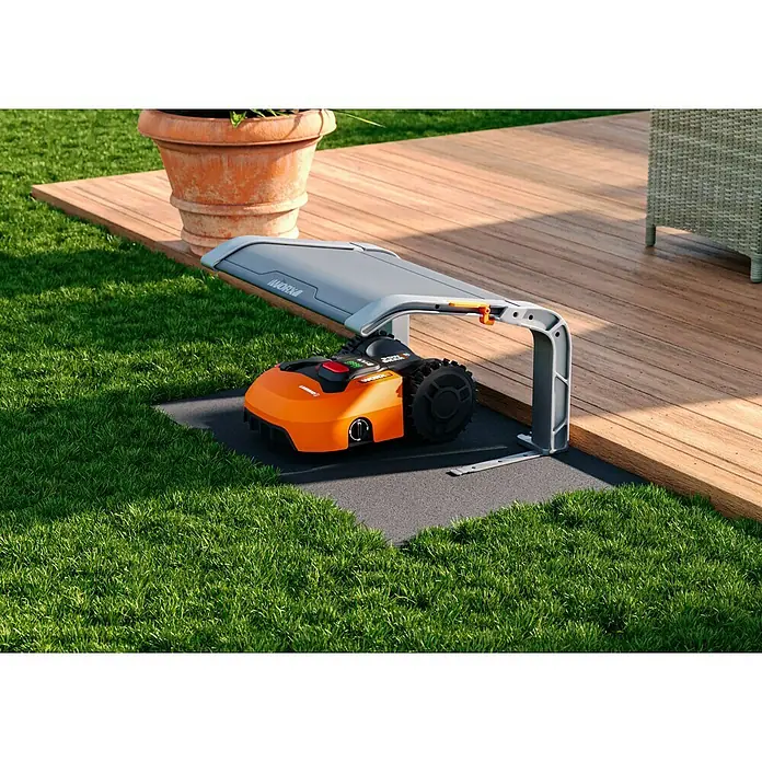Worx PowerShare 20V Mähroboter-Set Landroid L2000 - 2.000 m², Schnittbreite: 22 cm, Induktionsgestützte Navigation, Begrenzungskabel - Der Worx Landroid Mähroboter mit Ladestation auf dem Rasen vor der Terrasse.