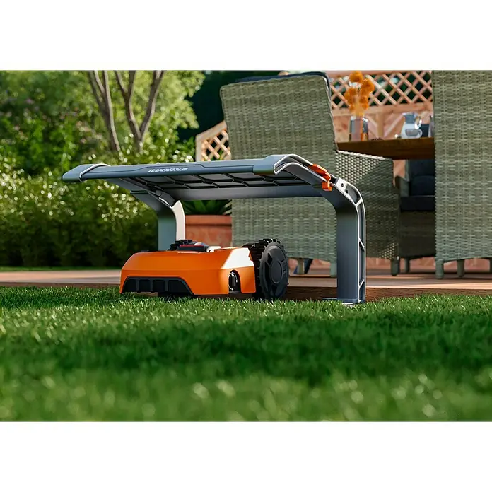 Worx PowerShare 20V Mähroboter-Set Landroid L2000 - 2.000 m², Schnittbreite: 22 cm, Induktionsgestützte Navigation, Begrenzungskabel - Nahaufnahme eines orangefarbenen WORX Landroid Mähroboters unter einem grauen Unterstand im Garten.