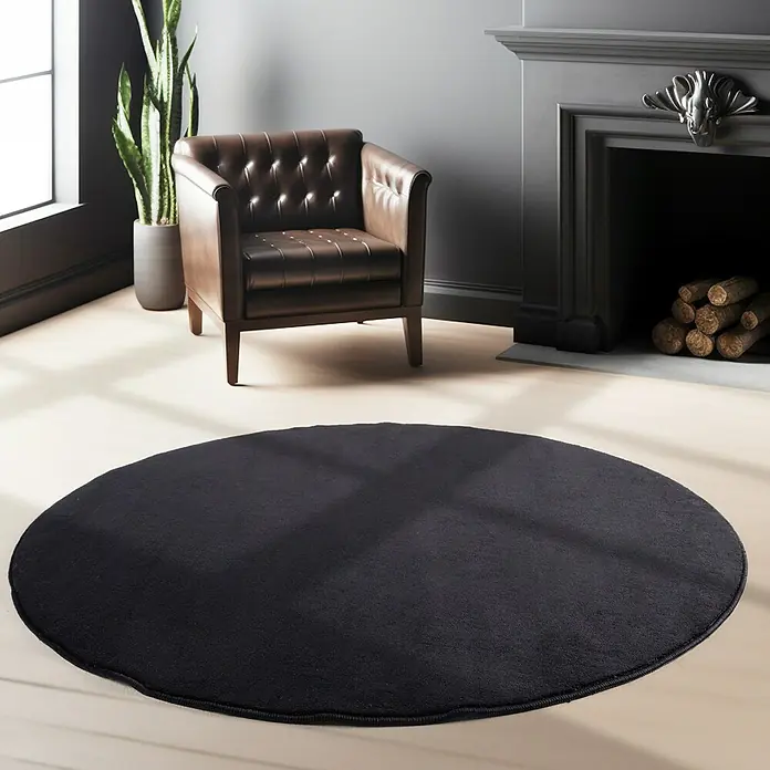 Kurzflorteppich Sky - Schwarz, Durchmesser: 160 cm, 100 % Polyester - Ein stilvoller Wohnbereich mit einem runden schwarzen Teppich als zentralem Element, umgeben von eleganten Möbeln und Dekorationen.