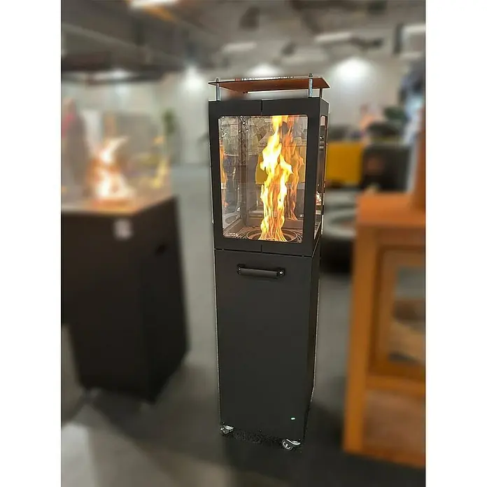 Nora Flames Estufa de pellets de exterior Ilios - 5 kW, Altura: 142 cm, Antracita - La imagen muestra un elegante calefactor de patio con carcasa de vidrio y llama. El calefactor se apoya sobre una base negra con ruedas.
