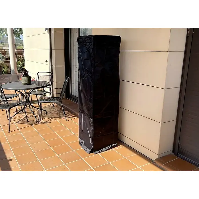 Nora Flames Estufa de exterior Babel - 10 kW, Altura: 155 cm - Una funda protectora negra se encuentra en un patio. La funda probablemente está protegiendo un mueble de las inclemencias del tiempo.
