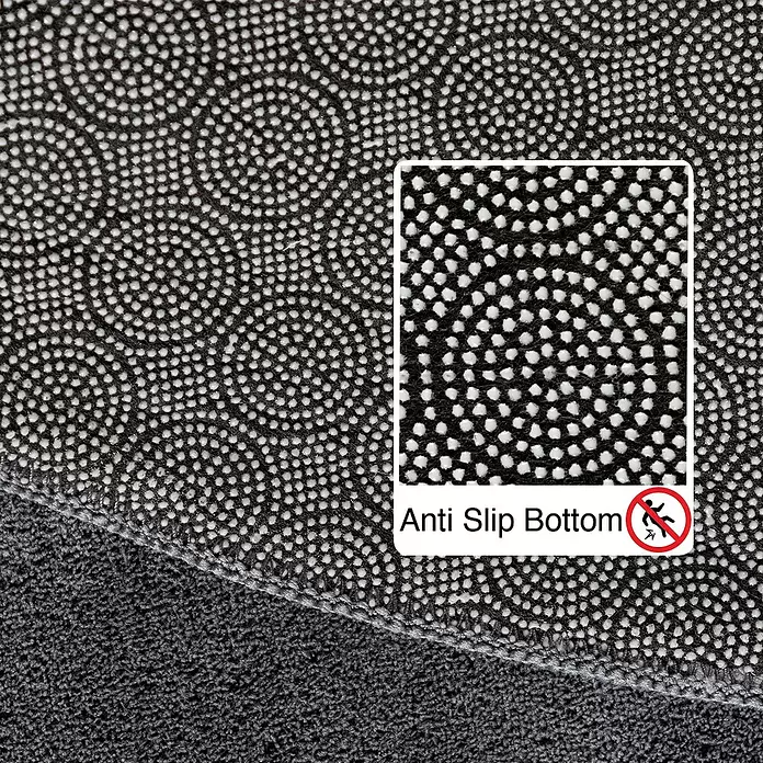 Kurzflorteppich Sky - Grau, Durchmesser: 120 cm, 100 % Polyester - Rutschfeste Unterseite eines dunkelgrauen Teppichs mit schwarzer Rückseite, weißen strukturierten Punkten und einem Anti-Rutsch-Symbol.