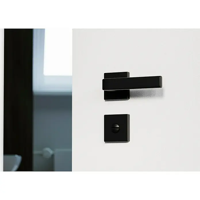 Hoppe Zimmertürgarnitur WC Dublin - Stärke Tür: 42 mm - 37 mm, Aluminium, Schwarz, Schlitzkopf/Olive - Nahaufnahme eines modernen, mattschwarzen Türgriffs und Schlosses auf einer weißen Tür, der minimalistisches Design betont.
