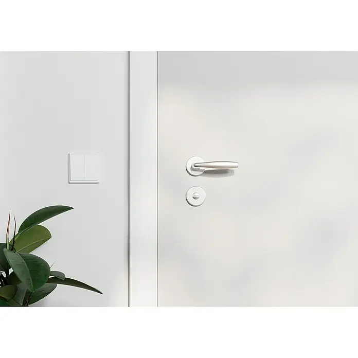 Hoppe Zimmertürgarnitur WC New York - Stärke Tür: 42 mm - 37 mm, Aluminium, Silber, Schlitzkopf/Olive - Nahaufnahme einer weißen Tür mit einem silbernen Türgriff und einem Lichtschalter an der angrenzenden Wand.