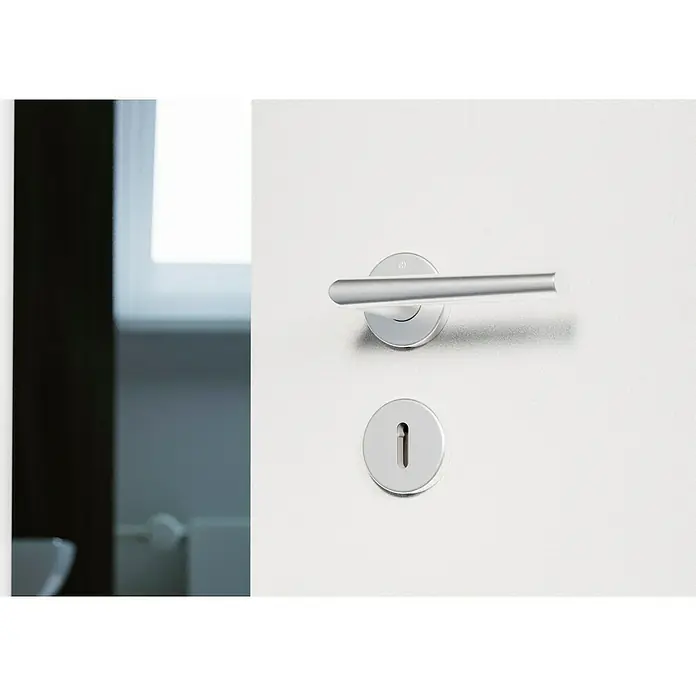 Hoppe Zimmertürgarnitur Stockholm - Stärke Tür: 37 mm - 42 mm, Aluminium, Buntbart - Nahaufnahme einer weißen Tür mit einem modernen, silbernen Türgriff und Schlüsselloch. Ideal für minimalistisches Design und Sicherheit.