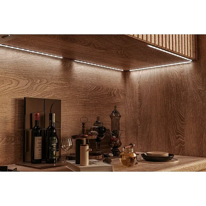 Tween Light Lichtleiste 4er Set - Länge: 160 cm, Lichtfarbe: Mehrfarbig, 0,15 W, Anzahl Leuchtmittel: 60 Stk. - Dieses Foto zeigt eine stilvolle Bar mit zwei Weinflaschen, Süßigkeiten und Honig unter einem beleuchteten Regal.
